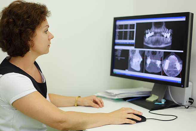 Dental hygienist looking at mouth x rays to assess TMJ treatments